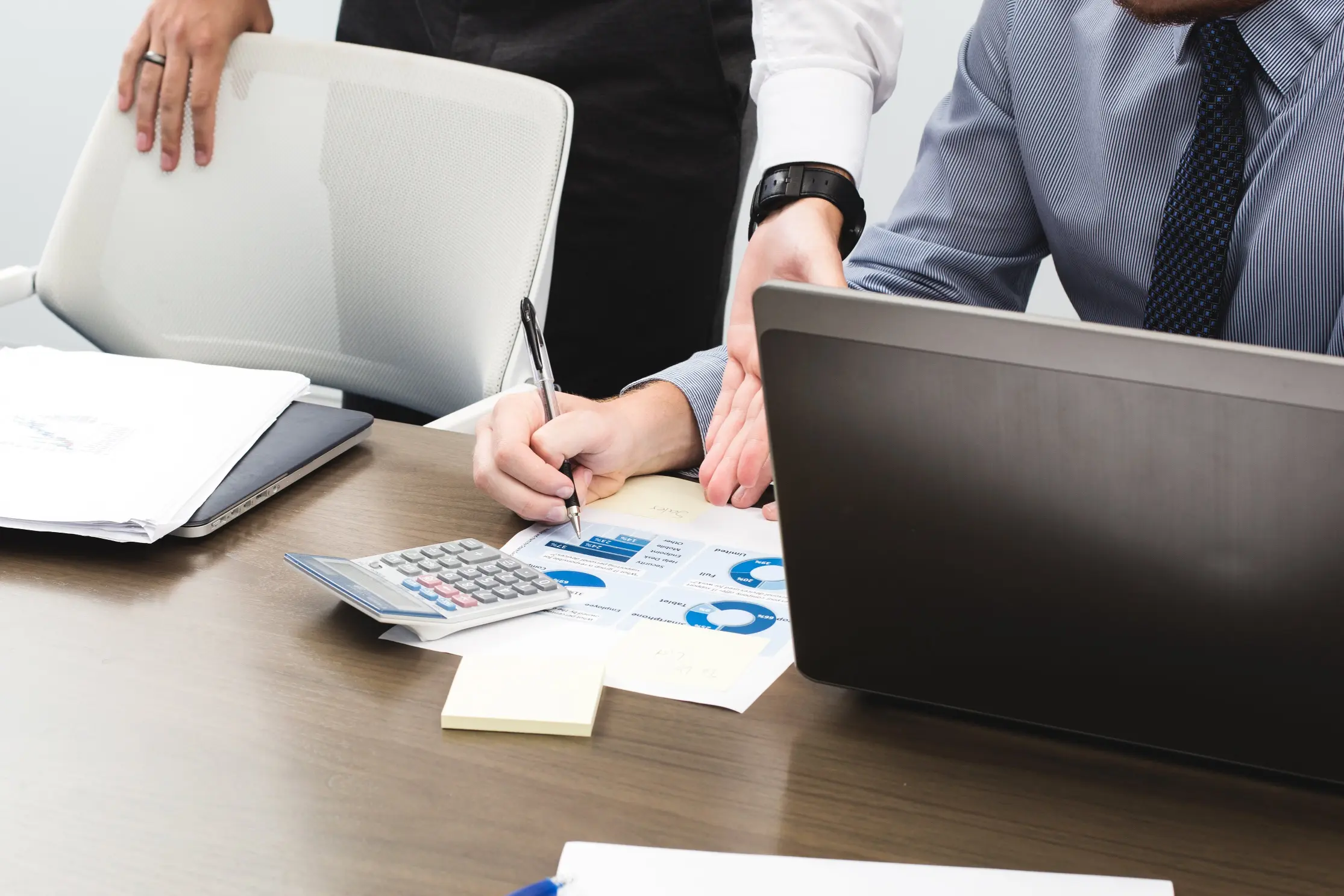Profesionales revisando informes financieros y usando un portátil en una gestoría Vitoria.