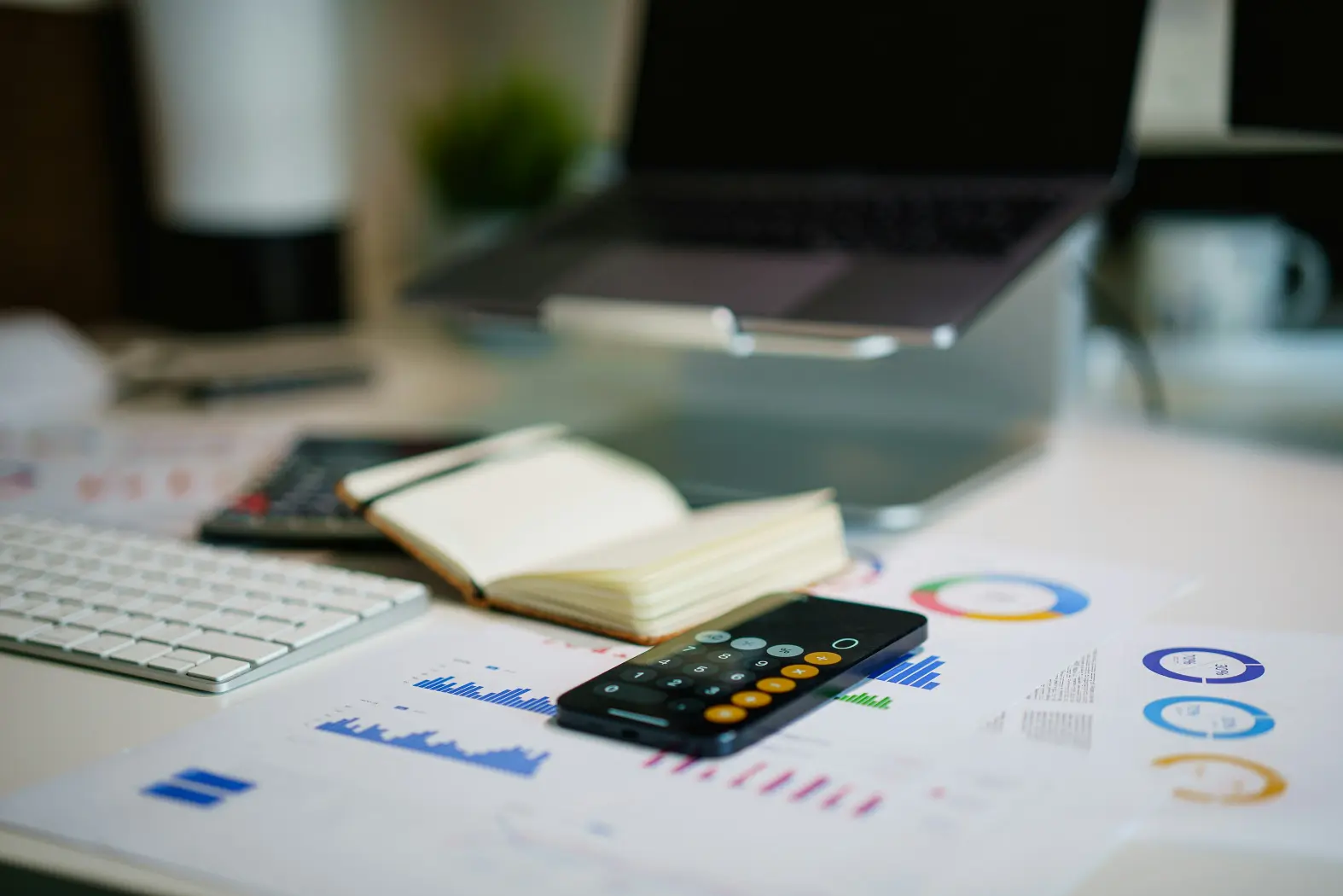 Espacio de trabajo con gráficos financieros, calculadora y ordenador, ideal para servicios de asesoría contable.